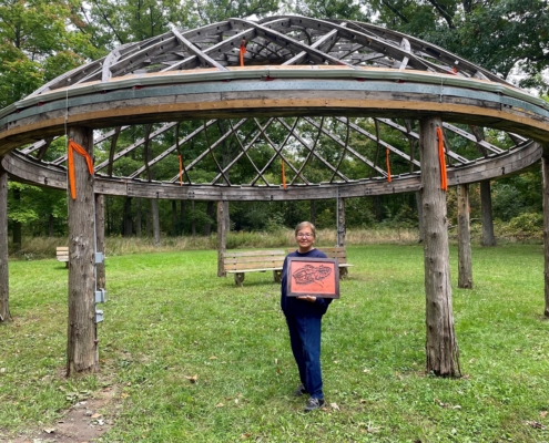 a person holding a sign standing under a pavilion with a park in the background
