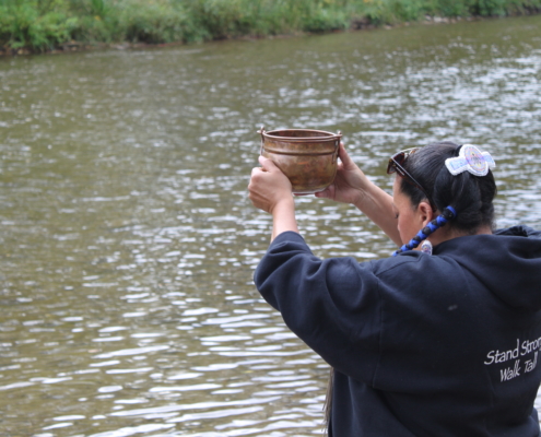 a person holding a pot over their head looking at the river